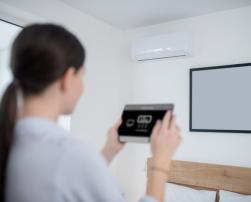 Woman turning air conditioning with tablet