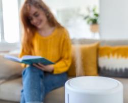 Air humidifier and woman reading a book on the sofa